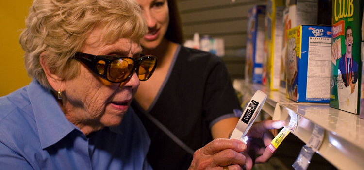 Photo of a woman using a magnifier while wearing blue blocker filter glasses.