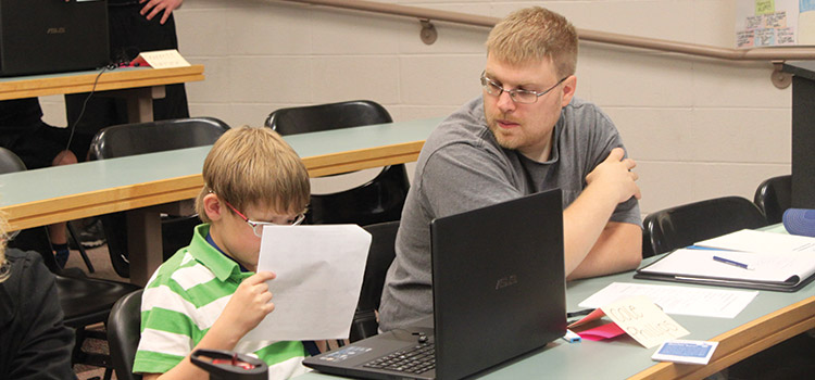 Child reading paper with older man