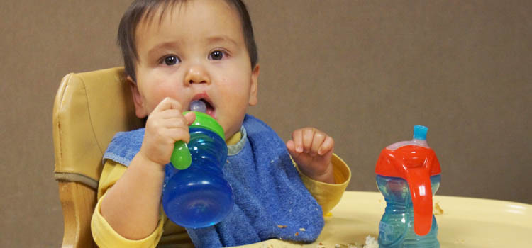 Infant mouthing a cup.