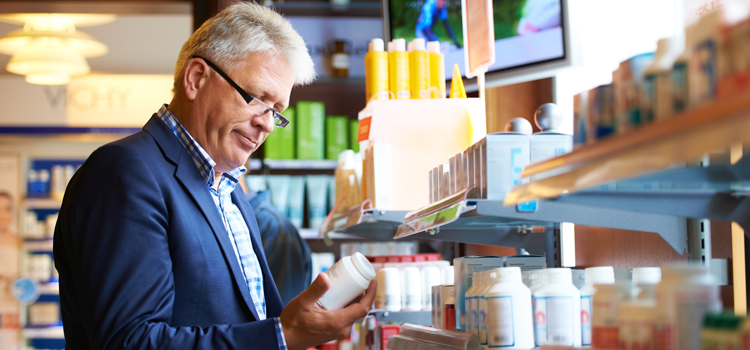 Older male reading the label on a pill bottle 