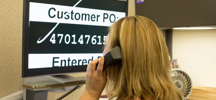 Photo of a woman looking at a CCTV magnification and listening on a phone