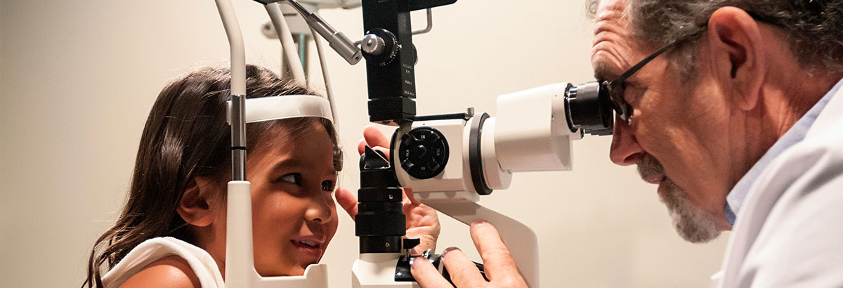 Dr. providing an eye exam for a little girl