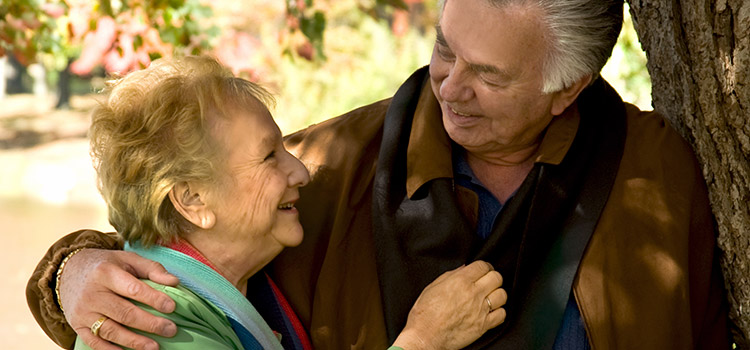 Elderly couple under tree smiling