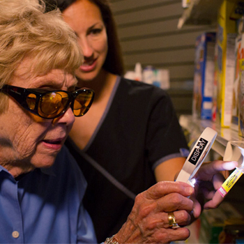 photo of an older women using a hand-held magnifer