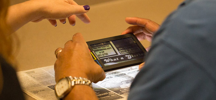 photo of a man using a hand held electronic magnifier